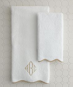 two white towels with monogrammed initials on them, one in gold and the other in white