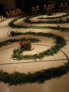 an arrangement of christmas wreaths on the floor in a room with rows of chairs