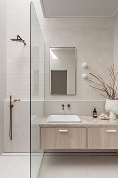 a white bathroom with two sinks and a shower head mounted on the wall next to it