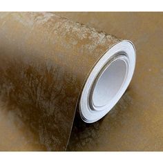 a roll of metallic foil on top of a brown wallpaper covered in gold and silver