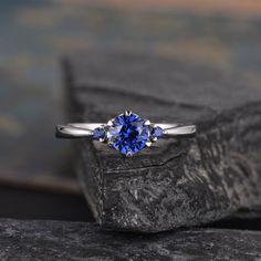 a blue sapphire ring sitting on top of a rock