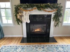 a living room with a fire place and christmas garland on the fireplace mantels