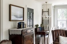 a living room filled with furniture and a chandelier hanging from the ceiling next to a window