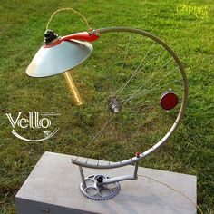 a bicycle wheel with a lamp attached to it on top of a box in the grass