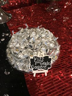 a bowl filled with silver foil covered candies on top of a red table cloth