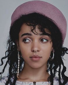 a woman with long hair wearing a pink hat and pearls on her nose is looking at the camera