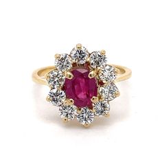 an oval shaped ruby and diamond cluster ring in yellow gold with diamonds surrounding the band