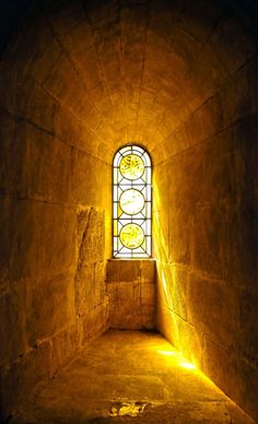 the light shines through a stained glass window in an old stone tunnel with steps leading up to it