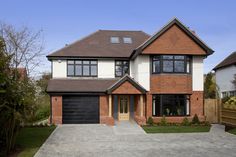 a two story brick house with black garage doors