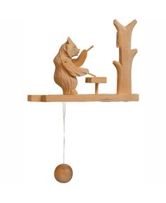 a wooden bear is playing with a toy on a tree branch hanging from the ceiling