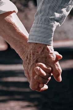 an older person holding the hand of a younger person