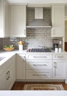 a kitchen with white cabinets and gray tile backsplash