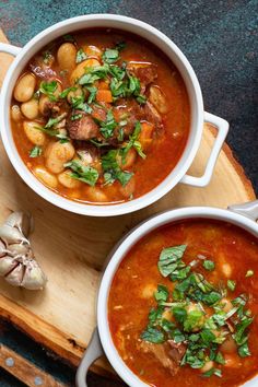 two white bowls filled with soup on top of a cutting board