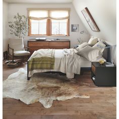 a bedroom with a bed, desk and chair in it next to a large cowhide rug