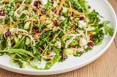 a white plate topped with salad on top of a wooden table