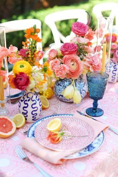 the table is set with plates and vases filled with flowers, lemons, and watermelon slices