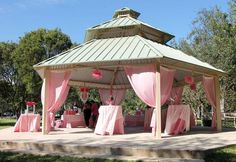 a gazebo with pink drapes and tables under it