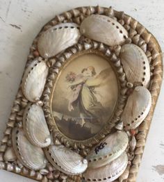 there is a shell frame with shells on the bottom and a painting in the middle