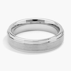 a white gold wedding ring on a plain surface with a rounded design in the center