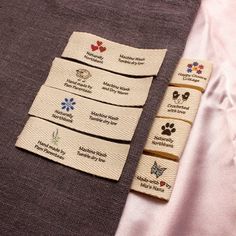 four tags with different designs on them are sitting on a cloth covered tablecloths