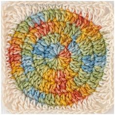 a crocheted square with multicolored yarn on it, in the shape of a circle