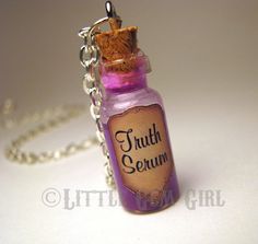 a small bottle necklace with the word truth sequin on it's front and back