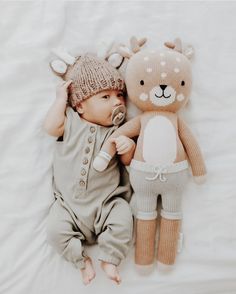 a baby laying next to a stuffed animal