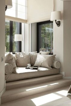 a white couch sitting in front of a window next to a lamp on a wall