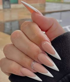 a woman's hand with some white and pink nail polish on her nails, holding an orange tip