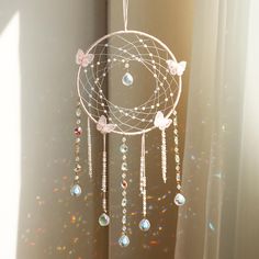 a white dream catcher hanging from the side of a window with sun shining through it