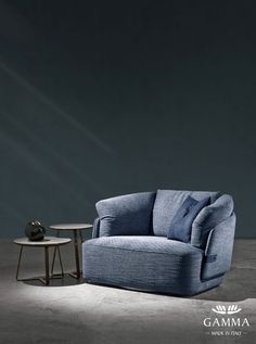 a blue couch sitting next to a small table on top of a cement floor in front of a black wall