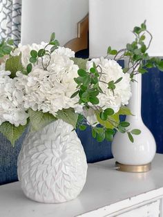 a white vase filled with flowers sitting on top of a dresser next to a mirror