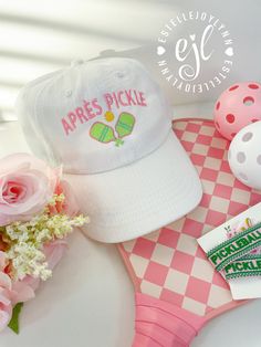 a white hat sitting on top of a table next to pink flowers and other items