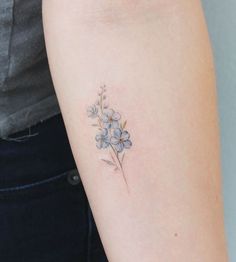 a small blue flower tattoo on the arm