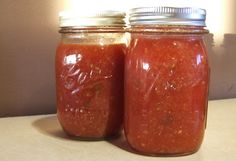 two jars filled with red sauce sitting on top of a counter