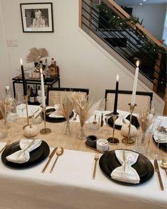 the table is set with black and white plates, napkins, silverware and candles