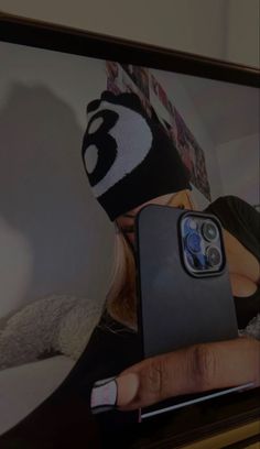 a person holding up a cell phone in front of a television screen with a panda face on it