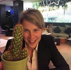 a smiling woman holding up a cactus in a pot