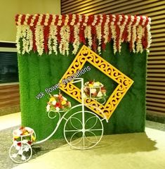 an elaborately decorated bike with flowers on the front and side is displayed in front of a green wall