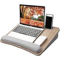 an open laptop computer sitting on top of a wooden desk next to a cell phone