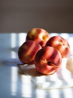 three peaches sitting on top of a white table