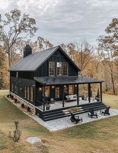 a large black house sitting on top of a lush green field