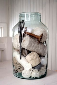 a glass jar filled with yarn and scissors