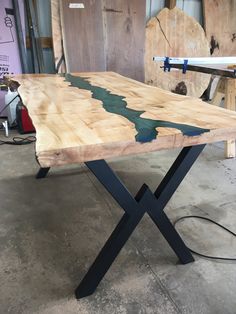 a wooden table with black metal legs in a workshop area next to other woodworking tools