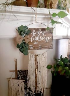 a wooden sign hanging from the side of a white mantle next to potted plants