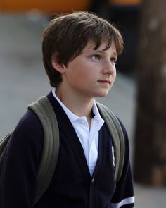 a young boy with a backpack looking off into the distance