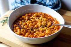 a white bowl filled with macaroni and cheese on top of a wooden cutting board