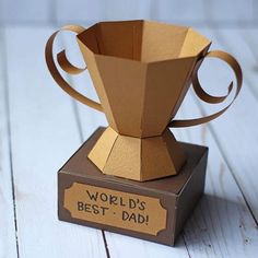 an origami coffee cup sitting on top of a wooden box that says world's best dad