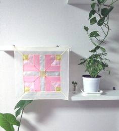 a potted plant sitting on top of a white shelf next to a wall hanging