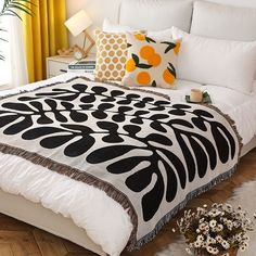 a bed with black and white comforter on top of it next to yellow curtains